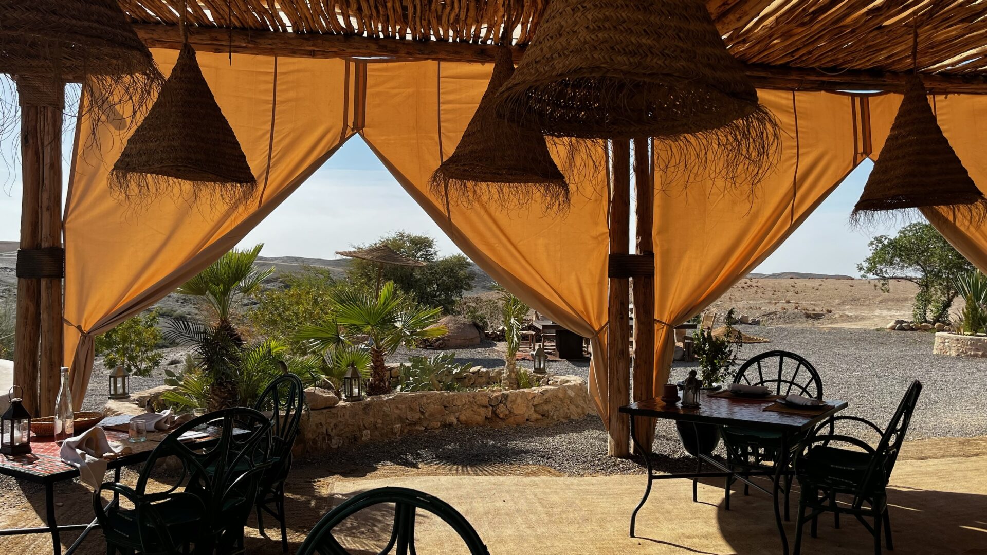 Terrasse ombragée aux voilages orange face au désert