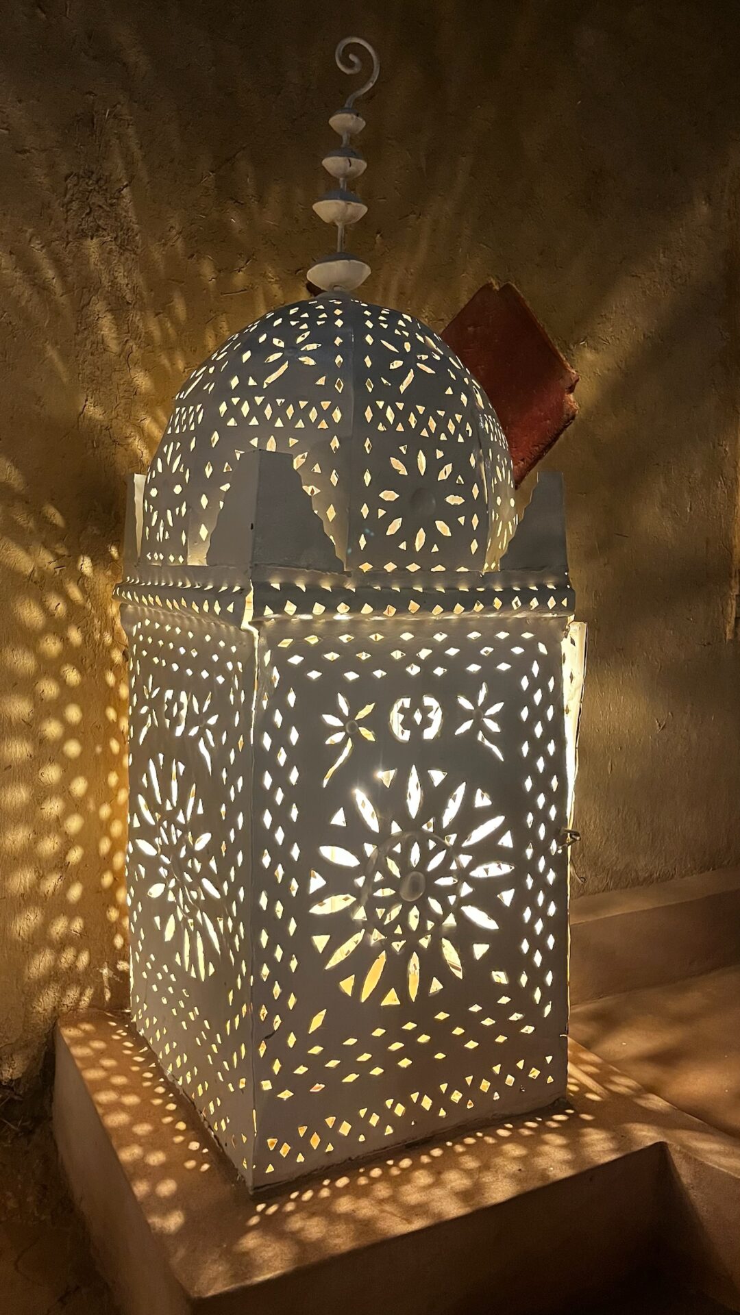Lanterne marocaine ajourée projetant des motifs de lumière
