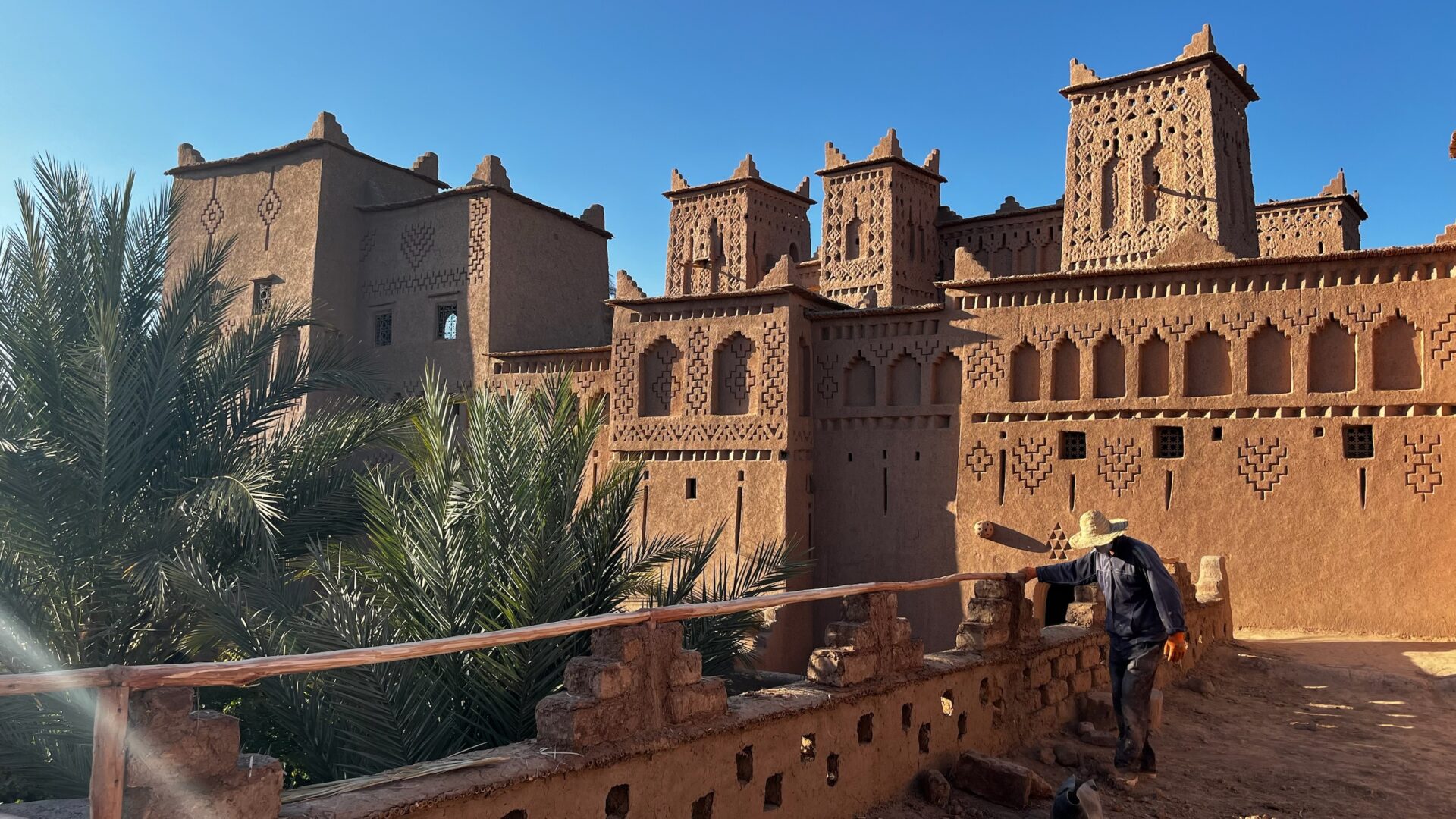 Kasbah ornée et palmiers sous un ciel bleu