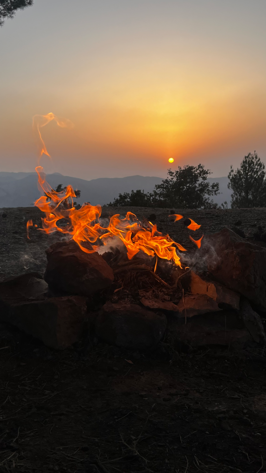 Feu de camp au coucher du soleil face aux montagnes