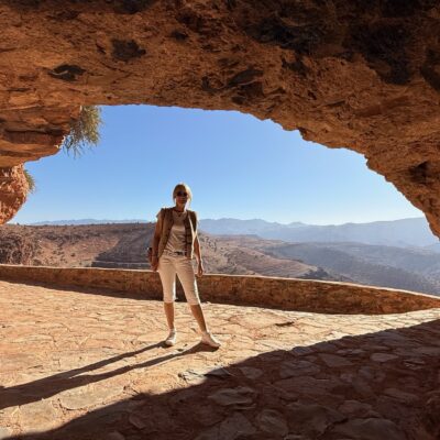 Voyageuse sous une arche rocheuse face aux montagnes
