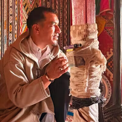 Hôte marocain servant le thé dans un salon traditionnel